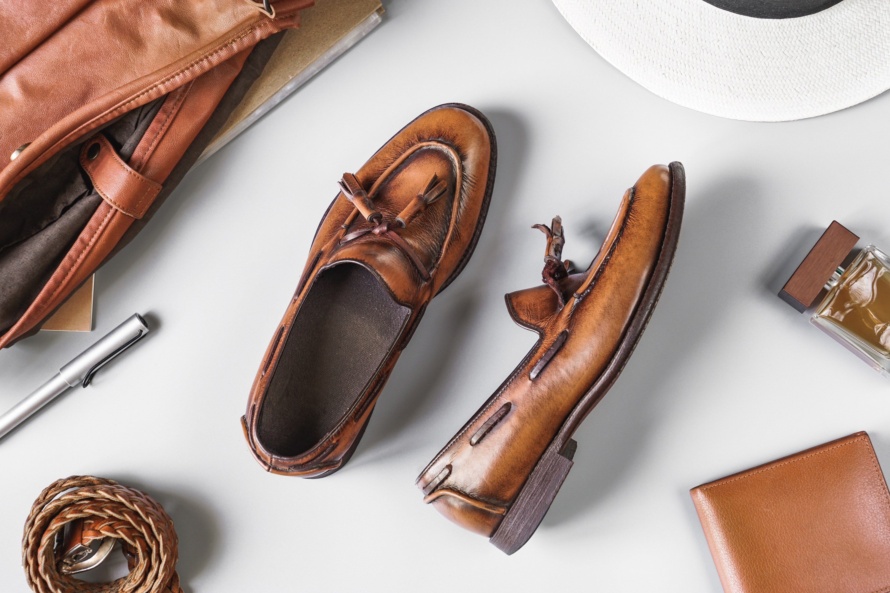 Top view of vintage brown tassel loafers and leather accesories on grey background, business casual items