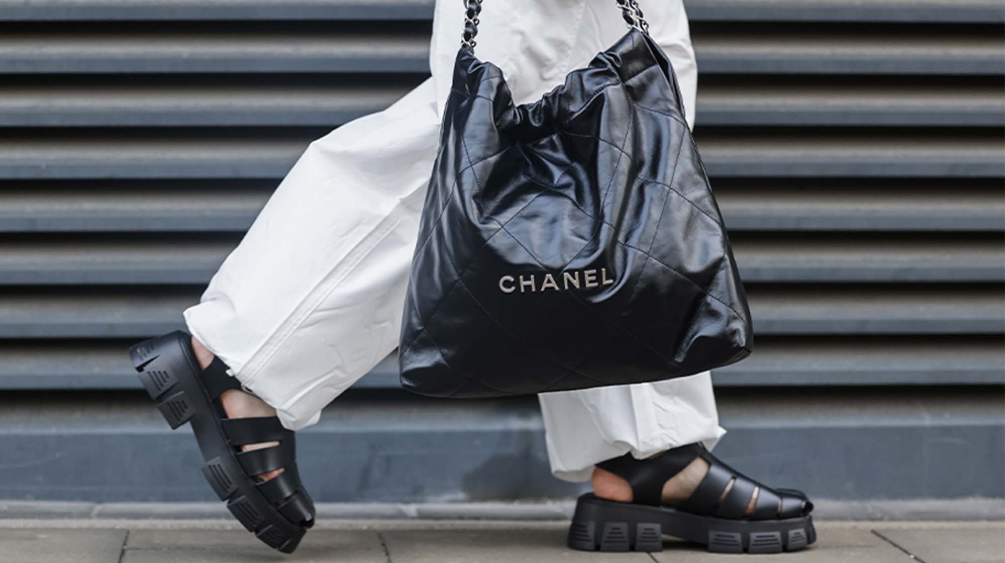 image of woman wearing white pants, a black tote bag, and black platform fisherman sandals