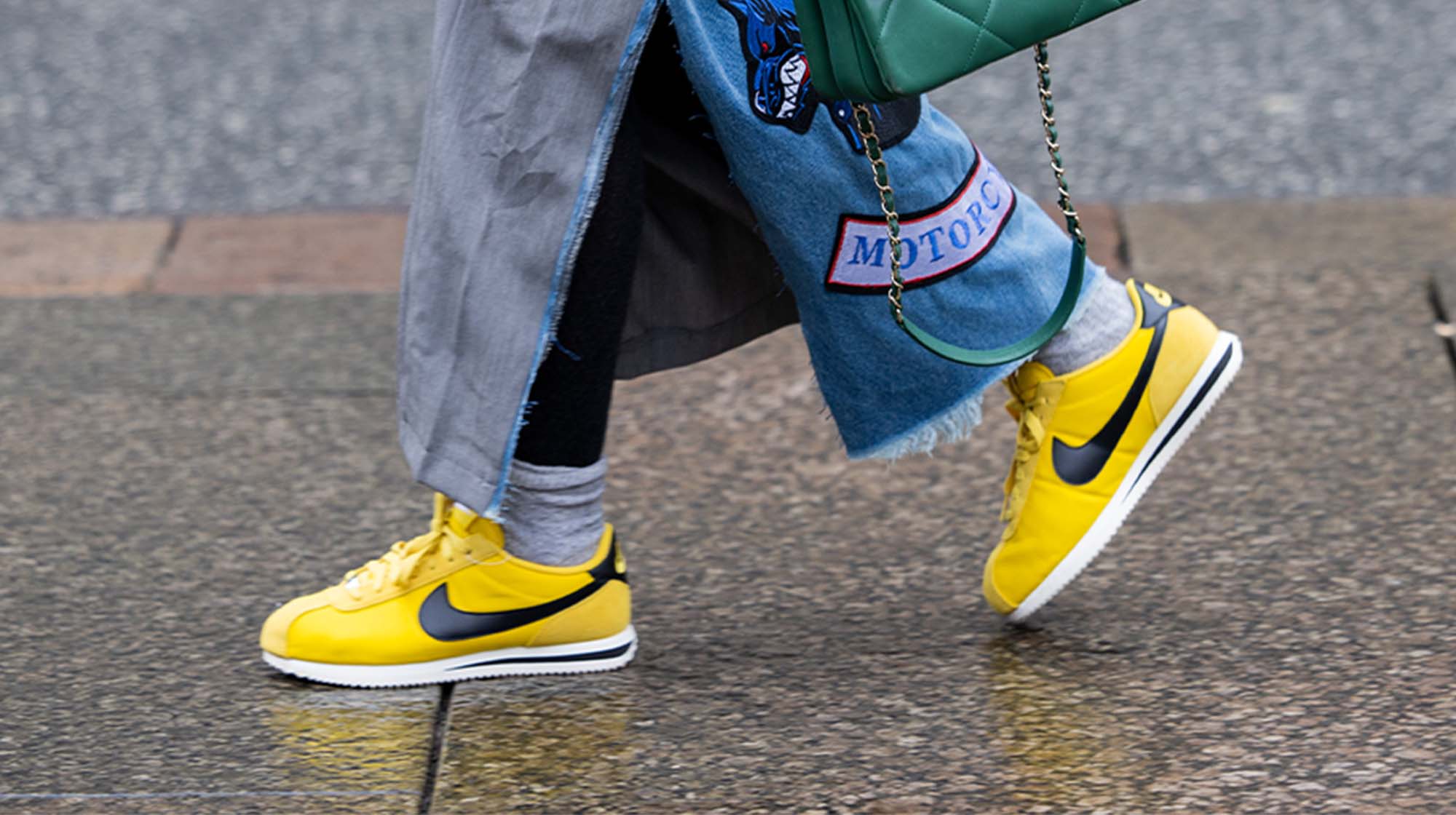 person wearing yellow sneakers with socks and a denim skirt