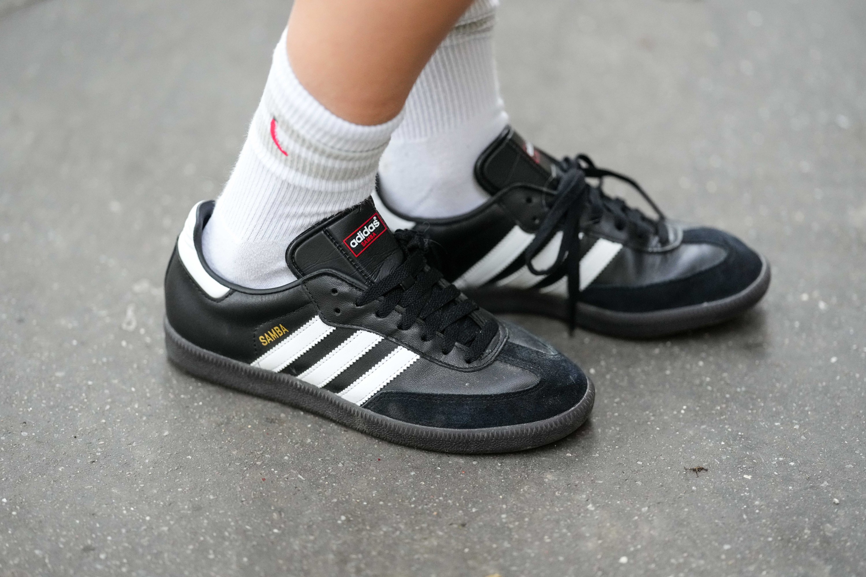 Woman wears white socks, black leather and suede Samba sneakers from Adidas, during a street style fashion photo