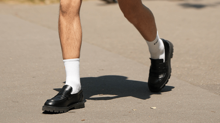 PARIS, FRANCE - JUNE 24: A guest wears black sunglasses, a white tank-top, a black short sleeves shirt from Balenciaga, black suit pants, a silver small chain bracelet from Tiffany, white socks, black shiny leather loafers , outside Hermes, during the Menswear Spring/Summer 2024 as part of Paris Fashion Week on June 24, 2023 in Paris, France.